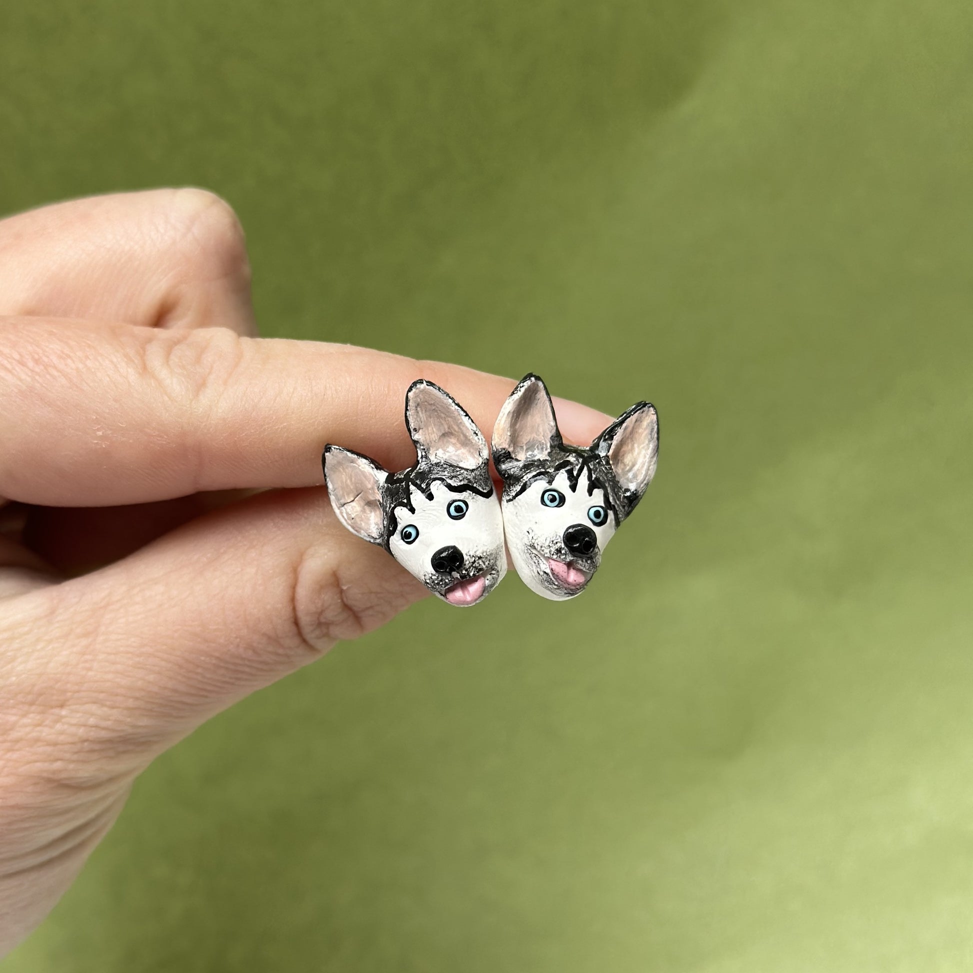 Handmade husky stud earrings by Pawfect Love, positioned in front of green background