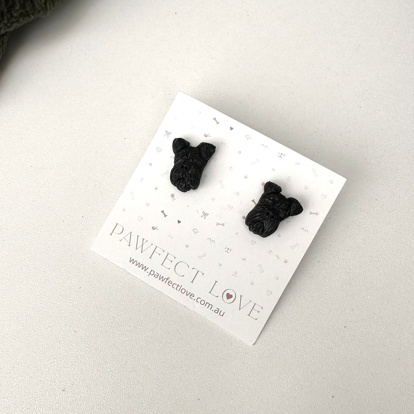 Black schnauzer dog-shaped earrings on a 'PAWfect Love' branded card against a light background