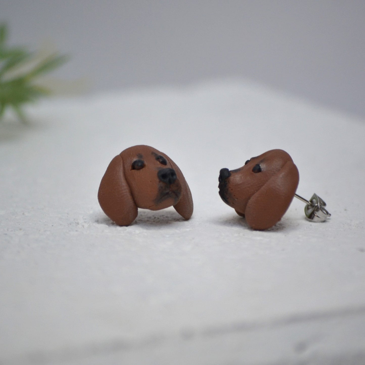 Handmade dachshund stud earrings by Pawfect Love, positioned on white paver