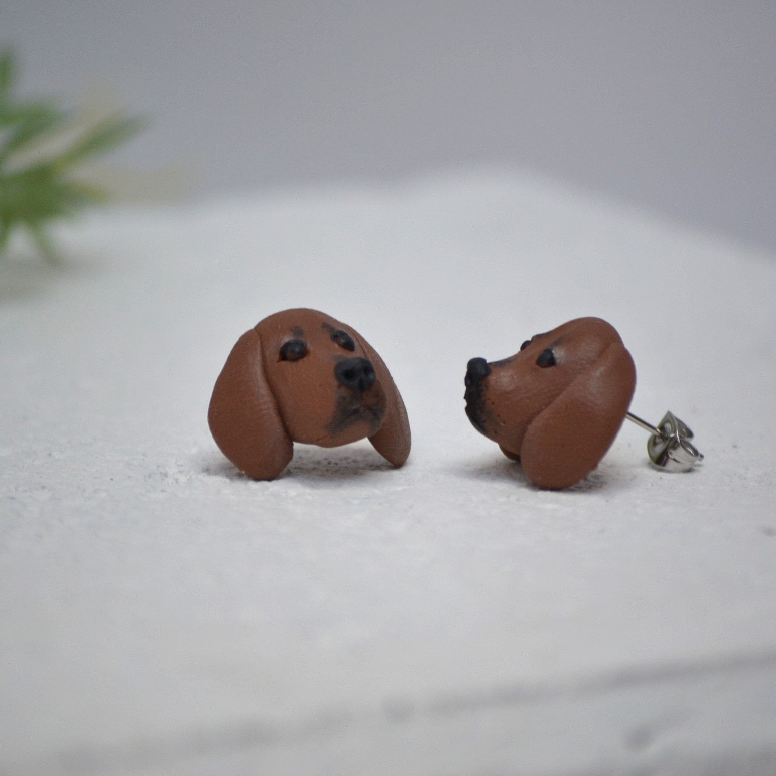 Handmade dachshund stud earrings by Pawfect Love, positioned on white paver