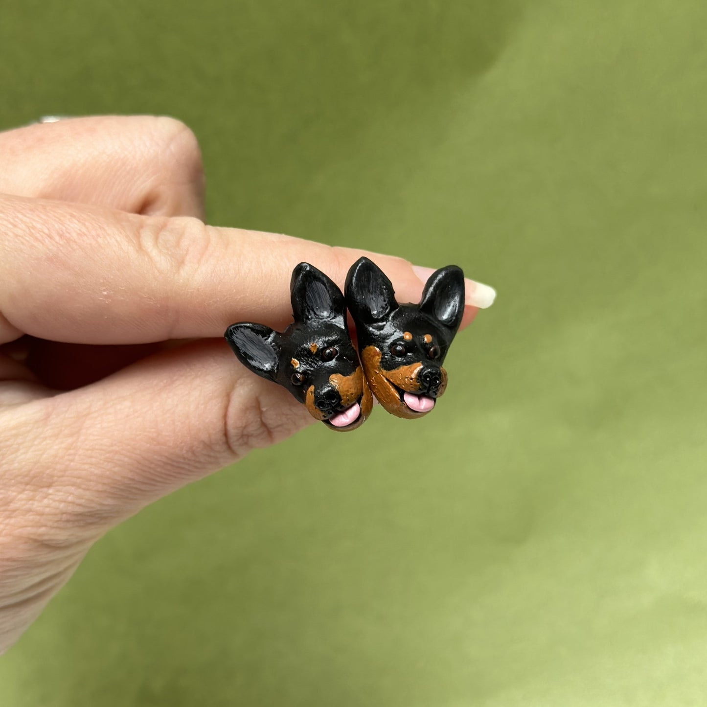 Handmade kelpie stud earrings by Pawfect Love, positioned in front of green background