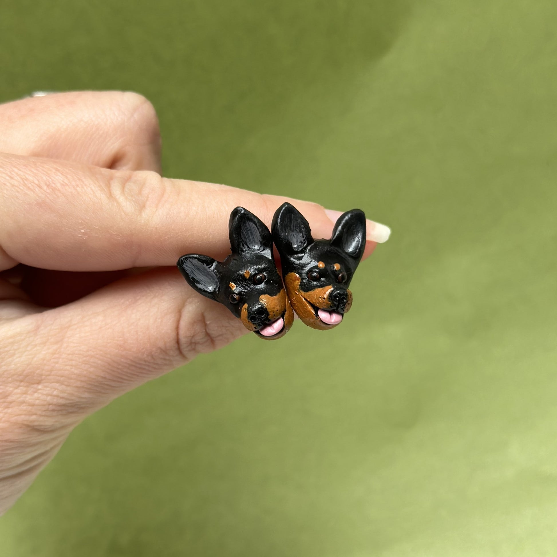 Handmade kelpie stud earrings by Pawfect Love, positioned in front of green background