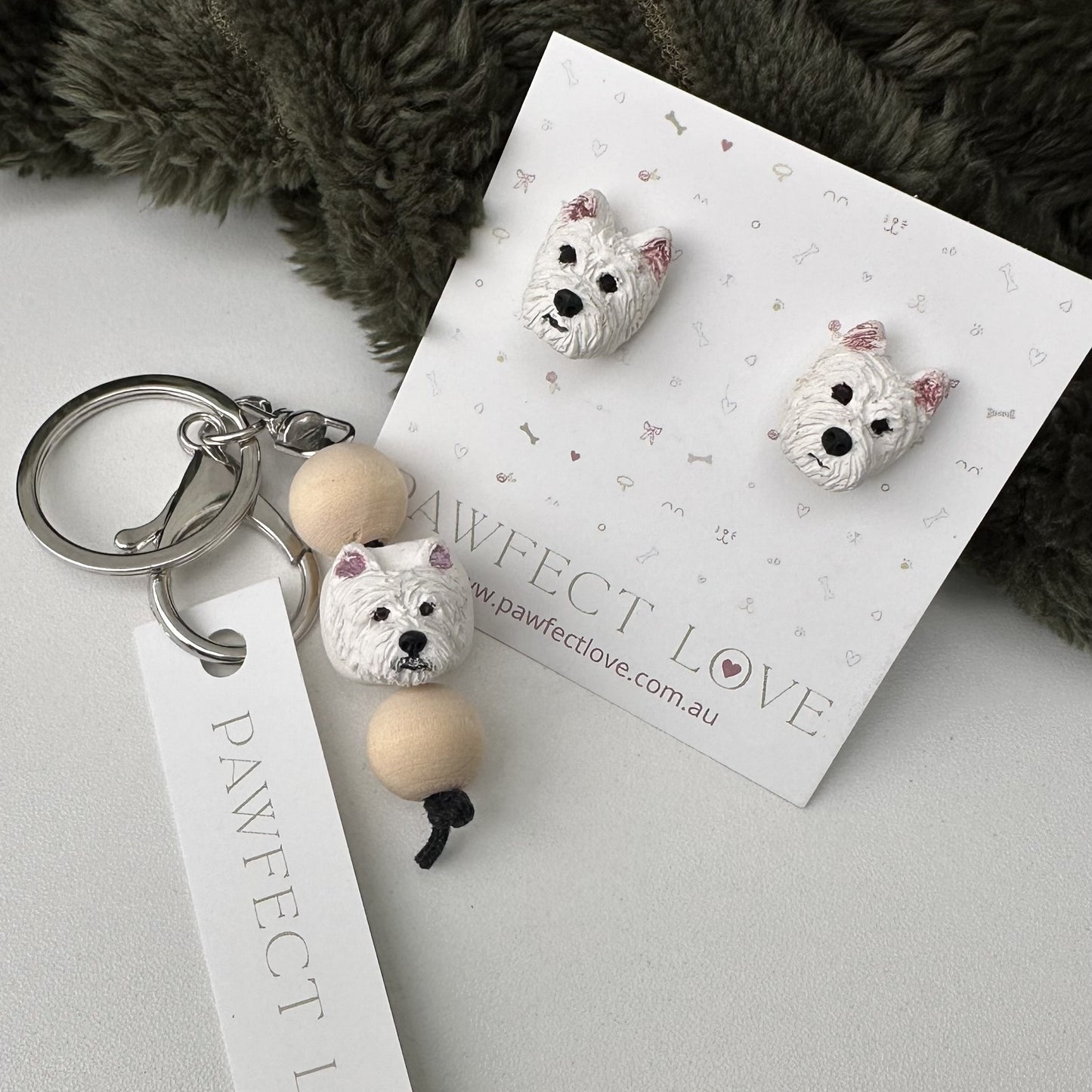 Westie Dog-shaped keychain and earrings on a 'Pawfect Love' branded card with a soft fabric background.