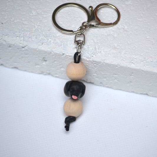 Handmade black labrador dog polymer clay and timber keying on white textured background