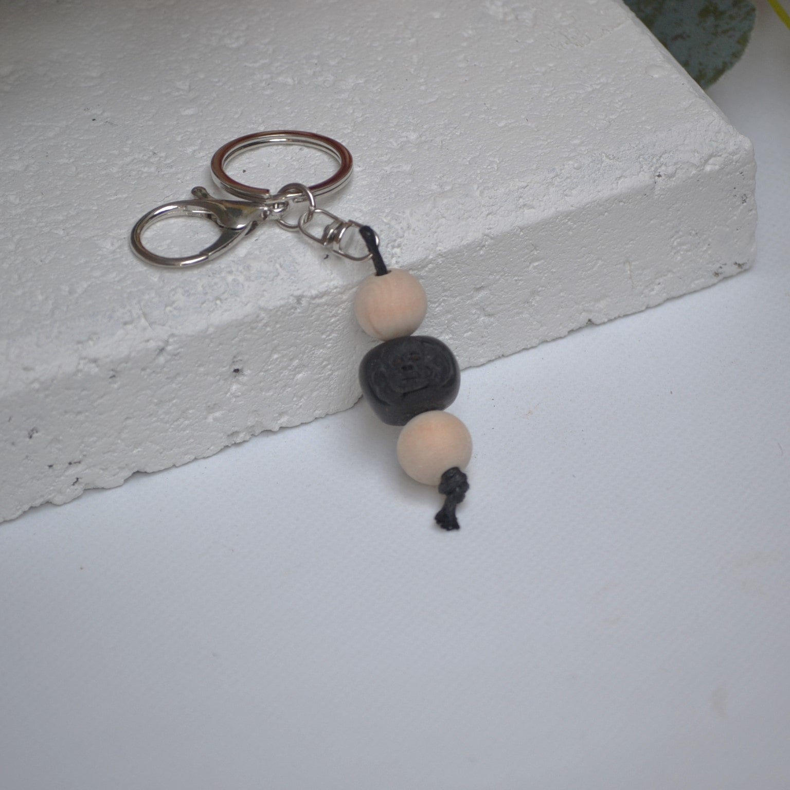 Handmade black poodle dog polymer clay and timber keying on white textured background