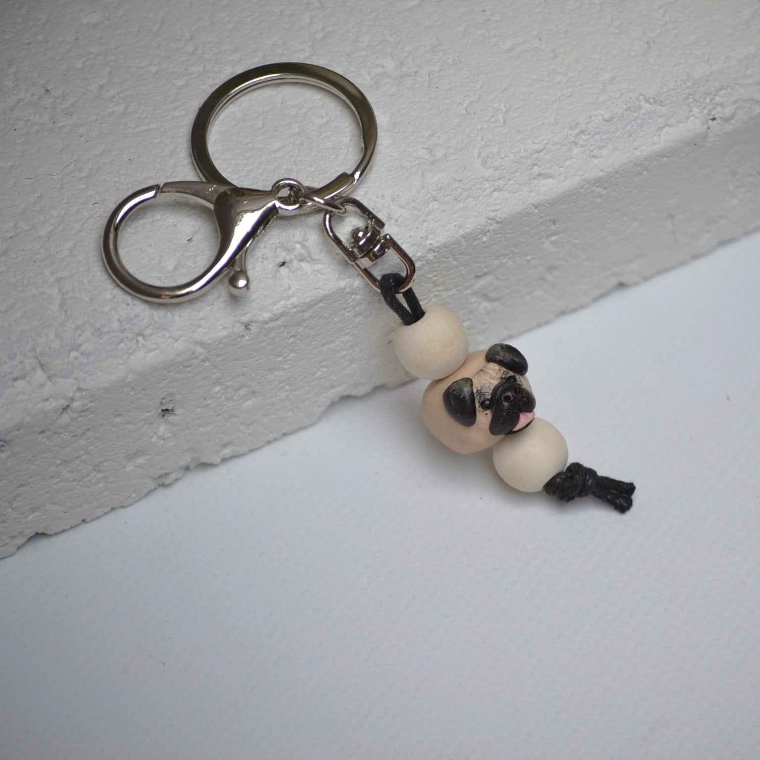 Handmade pug polymer clay and timber keying on white textured background