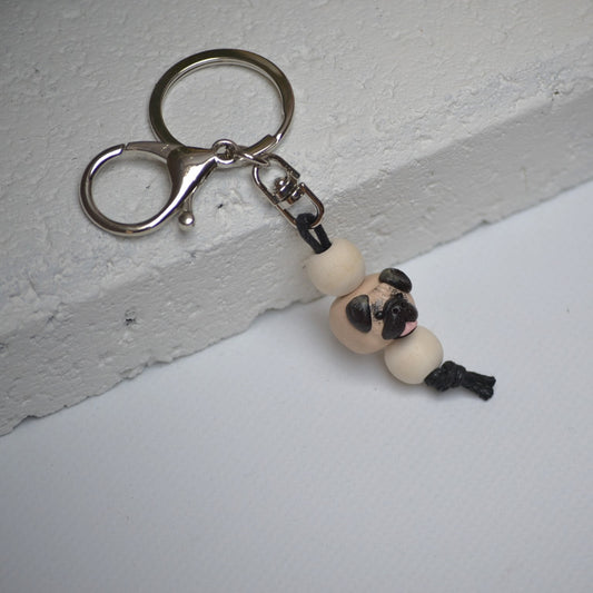 Handmade pug polymer clay and timber keying on white textured background