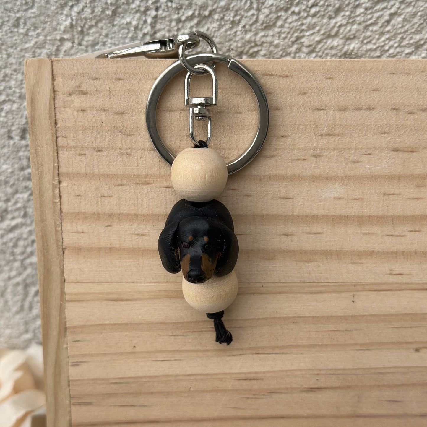 Keychain with a dachshund dog figure and wooden beads on a wooden surface