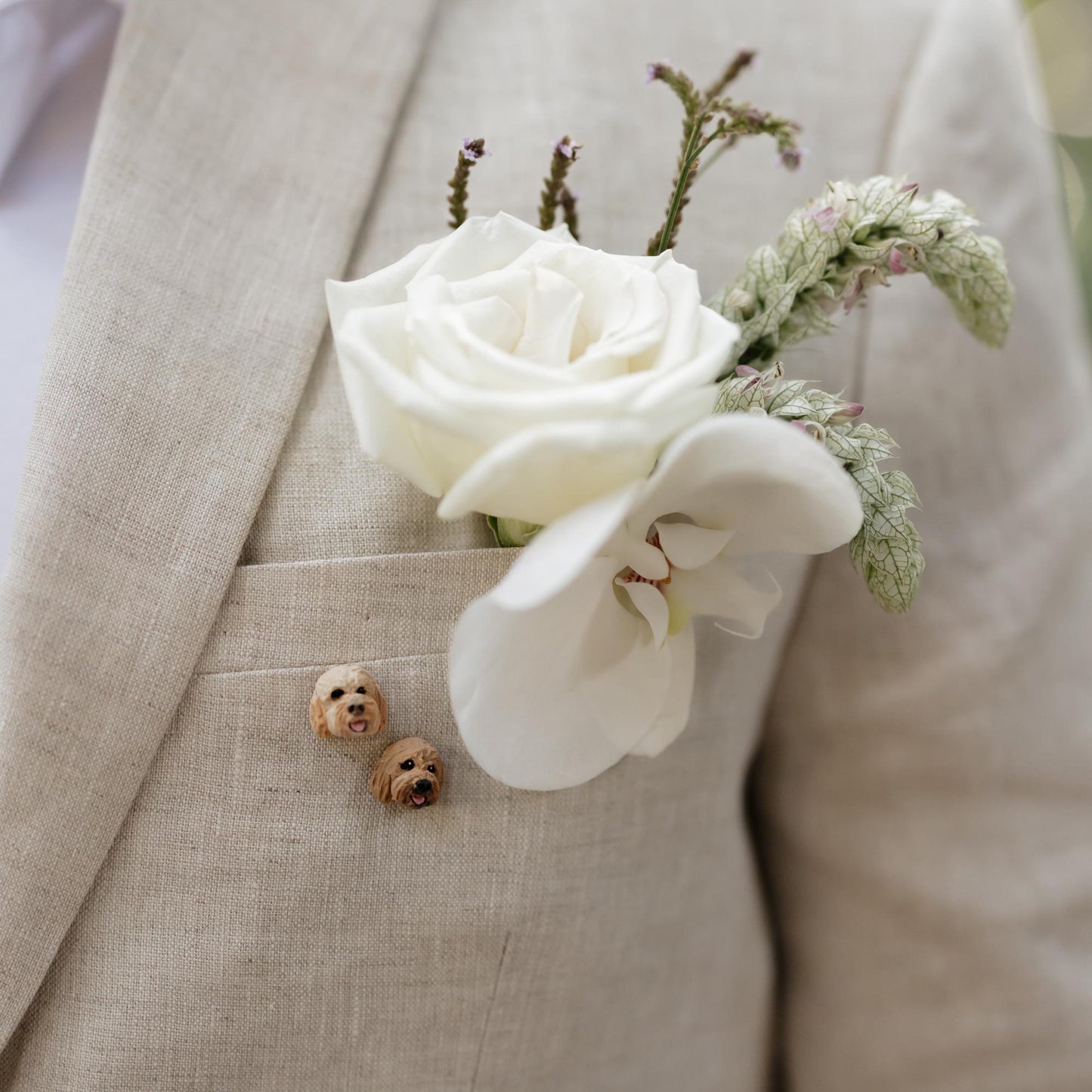 Cream coloured suit showing custom pet lapel pins of two dogs' faces.