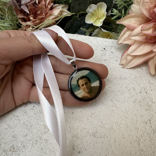 Memorial photo charm of father for bridal bouquet, pictured in front of florals.