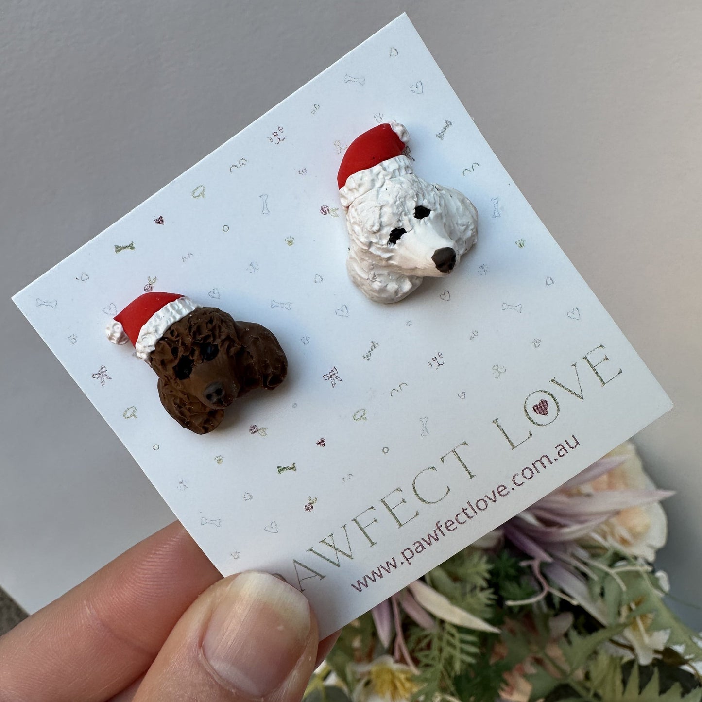 Handmade mismatched custom poodle dog stud earrings wearing santa hats.