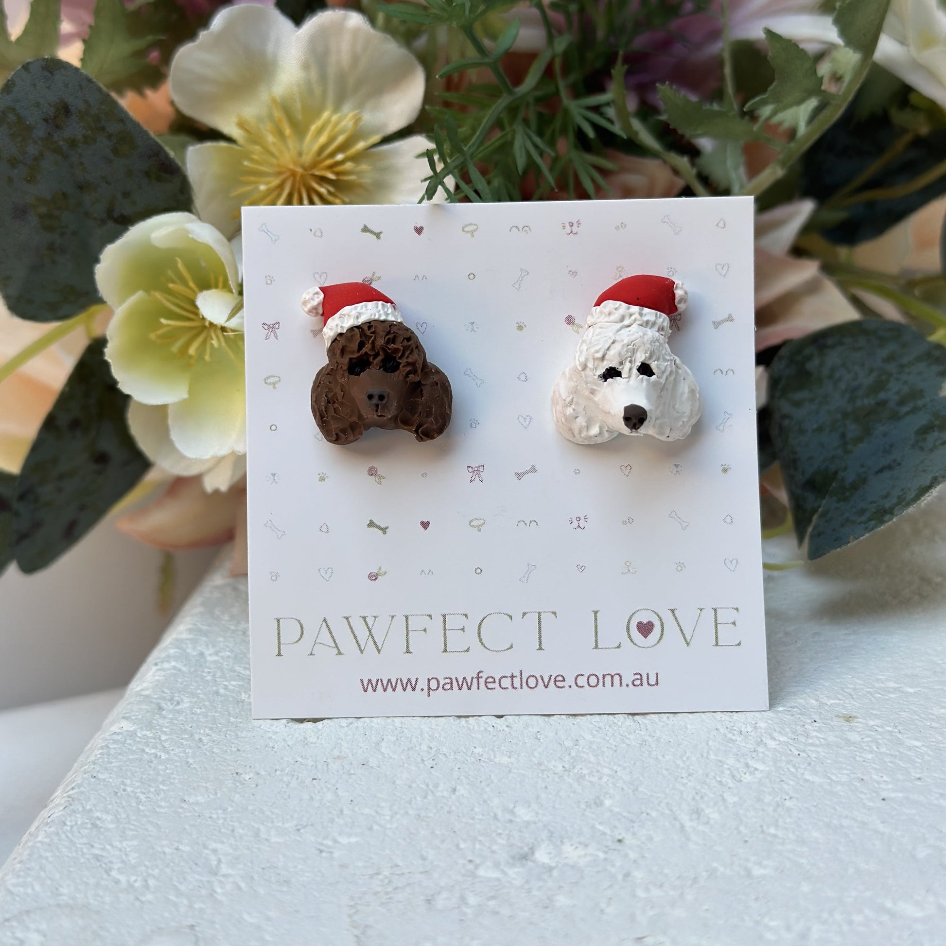 Handmade mismatched custom poodle dog stud earrings wearing santa hats.