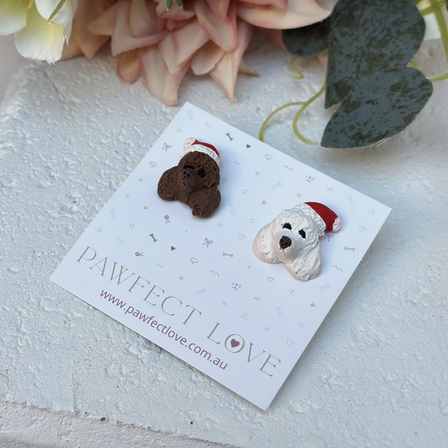 Handmade mismatched custom poodle dog stud earrings wearing santa hats.