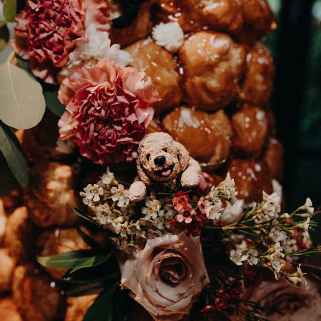 Dog cake topper cavoodle peeking out of a croquembouche.