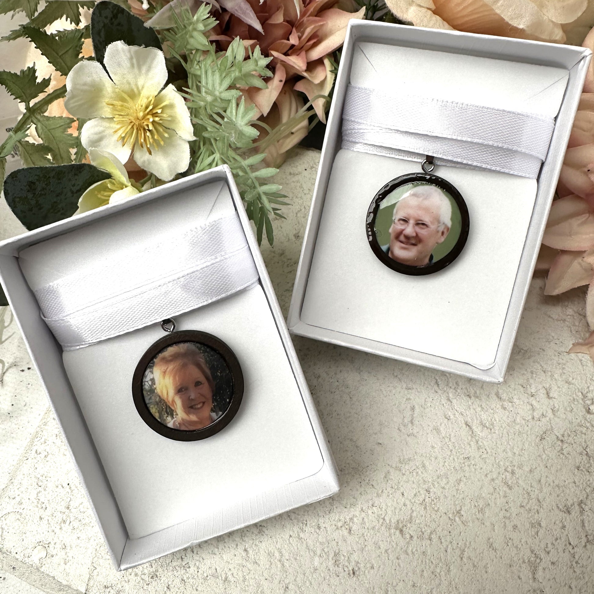 Memorial photo charms of father and grandmother for bridal bouquet, pictured in white giftboxes.