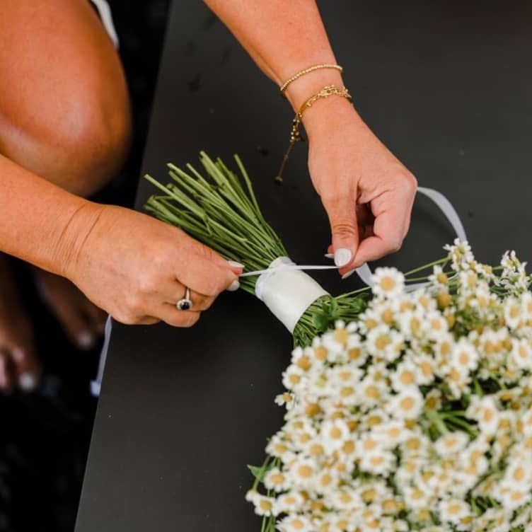 Timber memorial photo charm being wrapped around bouquet by bride.
