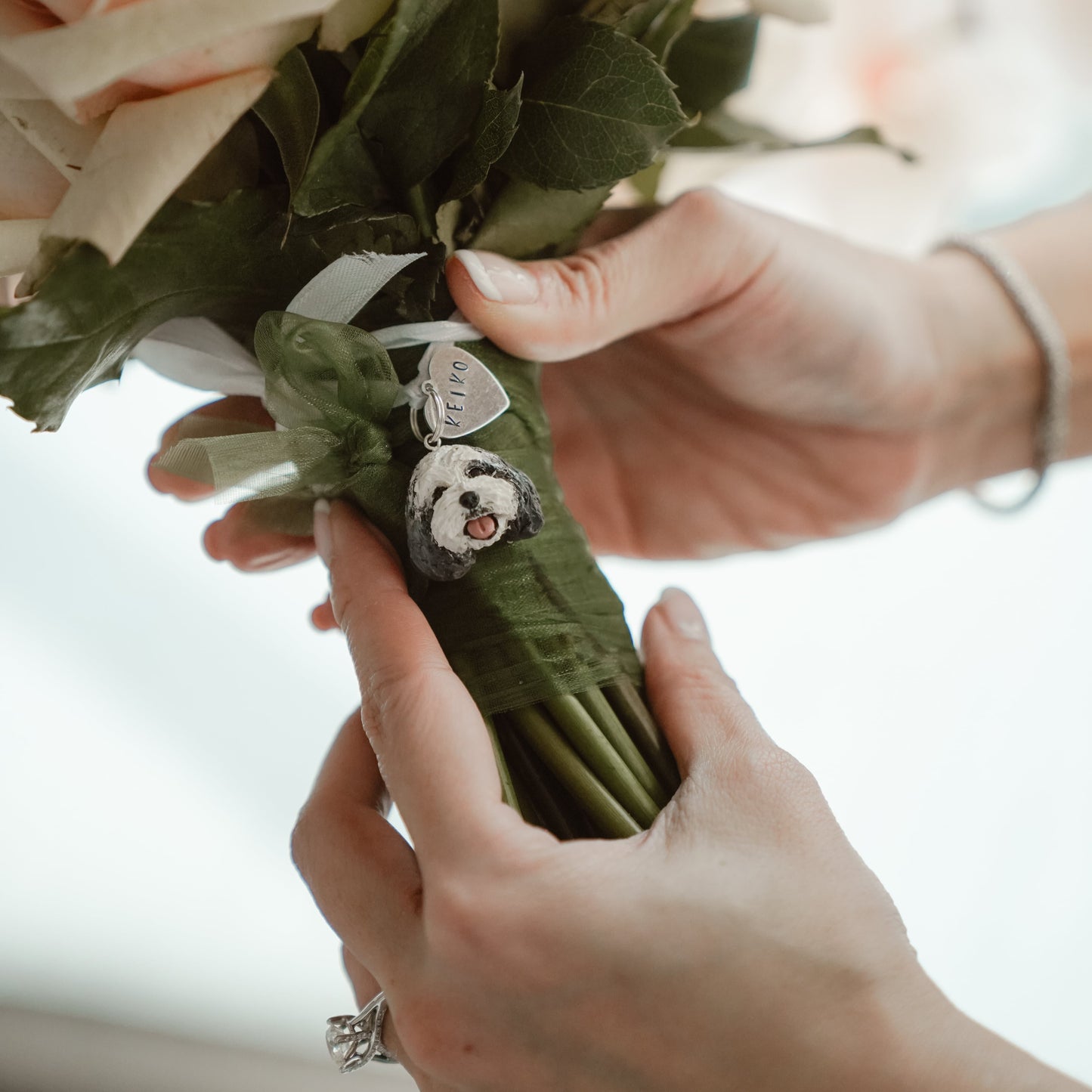 Custom pet bridal bouquet charm photo from a wedding day, featuring a cavoodle face and heart name tag..