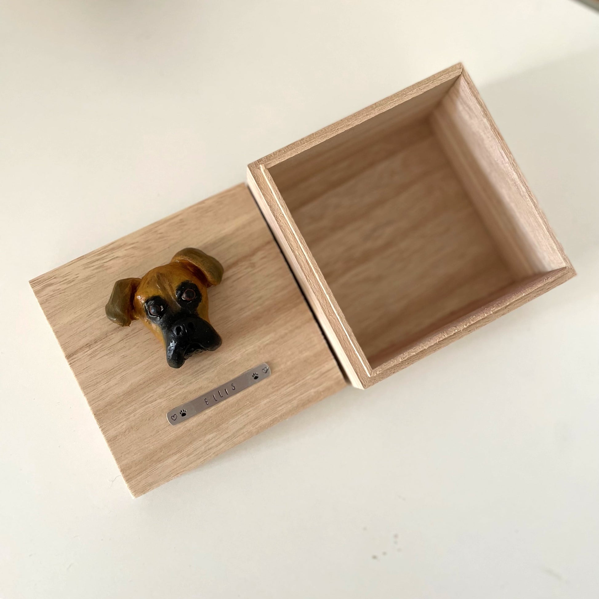 Custom timber pet memorial keepsake box with handscultped dog face on the lid, with a name plaque reading Ellis.