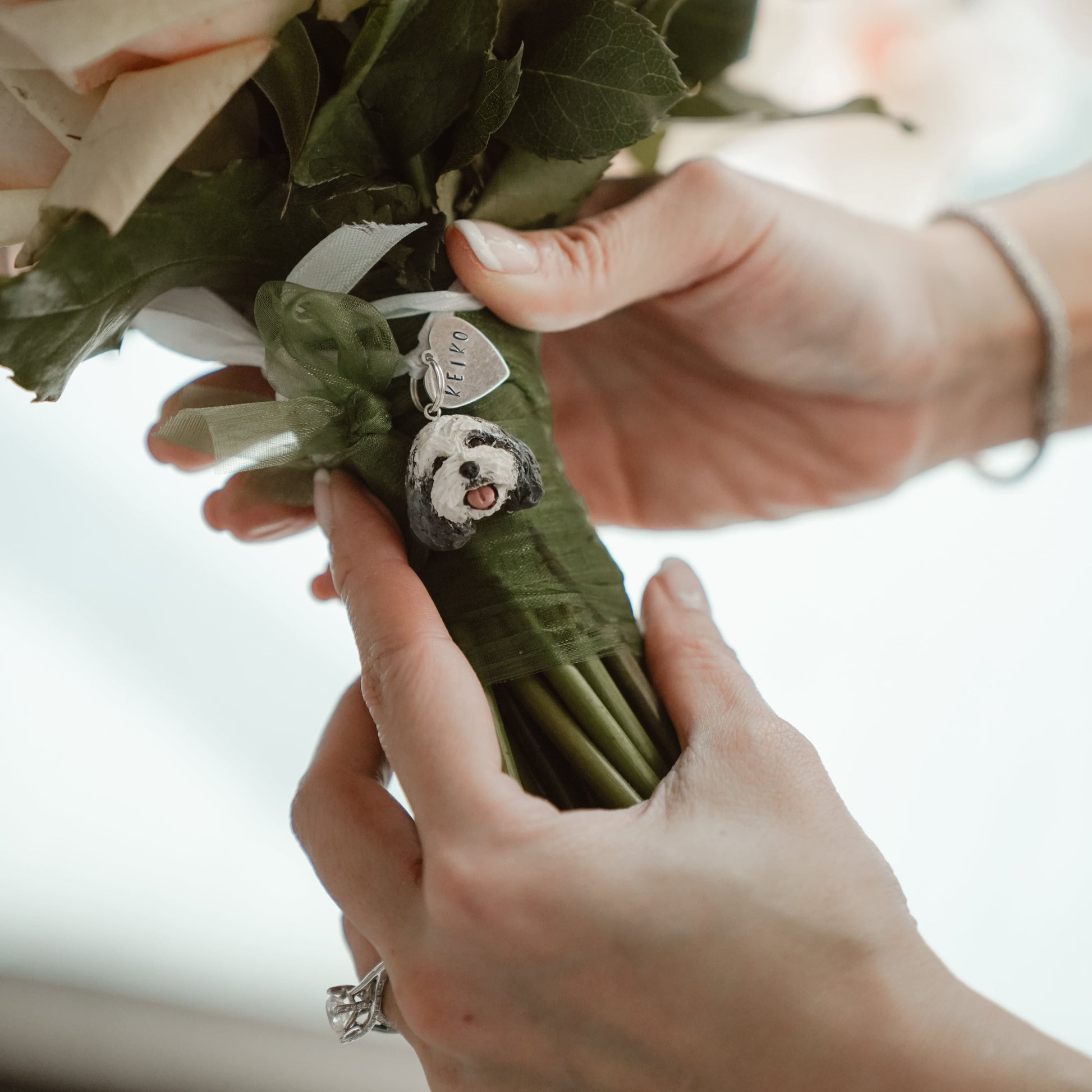 Metal hand-stamped bouquet pendant charm and handmade small dog face pendant hanging around stems of bouquet, displaying the name Keiko.