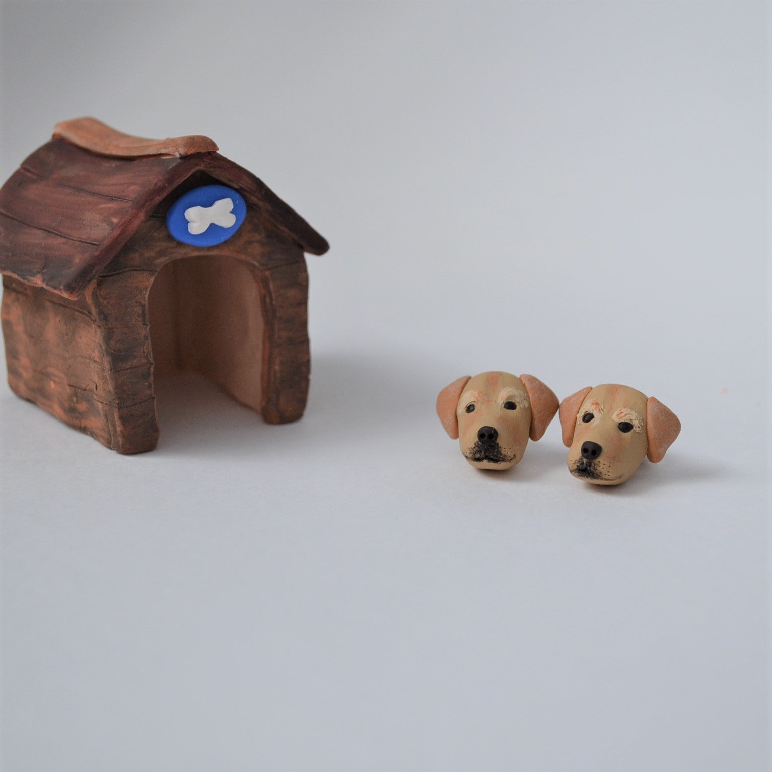 Handmade polymer clay golden lab retriever stud earrings shown styled beside mini kennel