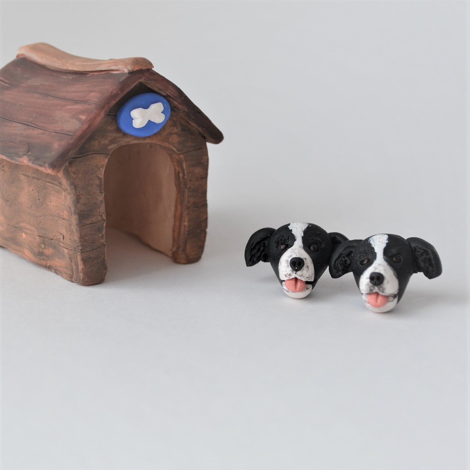 Handmade polymer clay border collie stud earrings shown beside mini kennel
