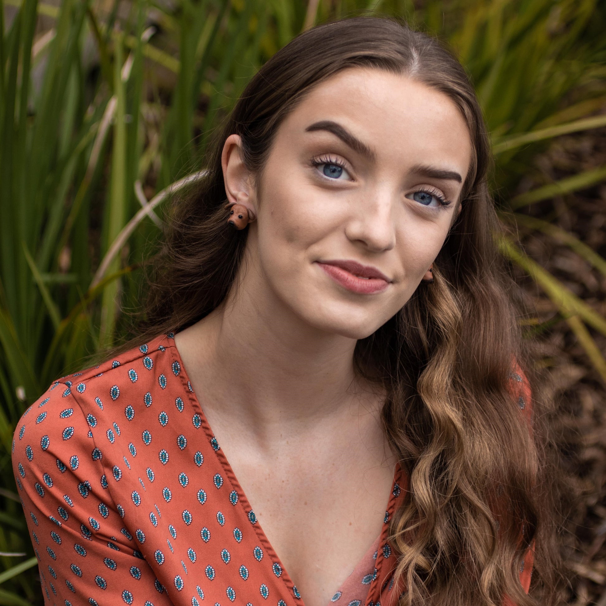 Handmade polymer clay Staffy stud earrings shown on model's ears