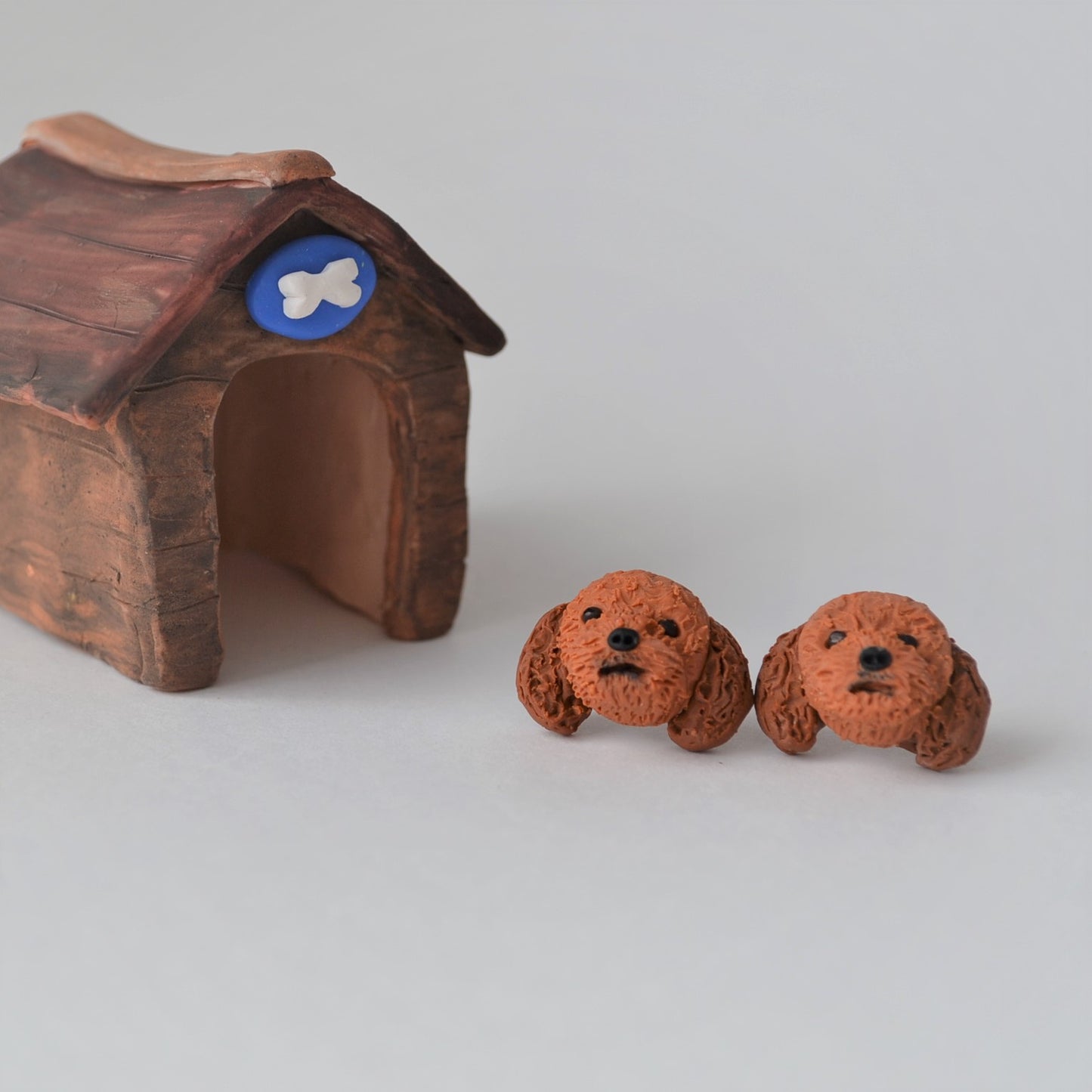 Handmade polymer clay Cavoodle stud earrings shown beside mini kennel