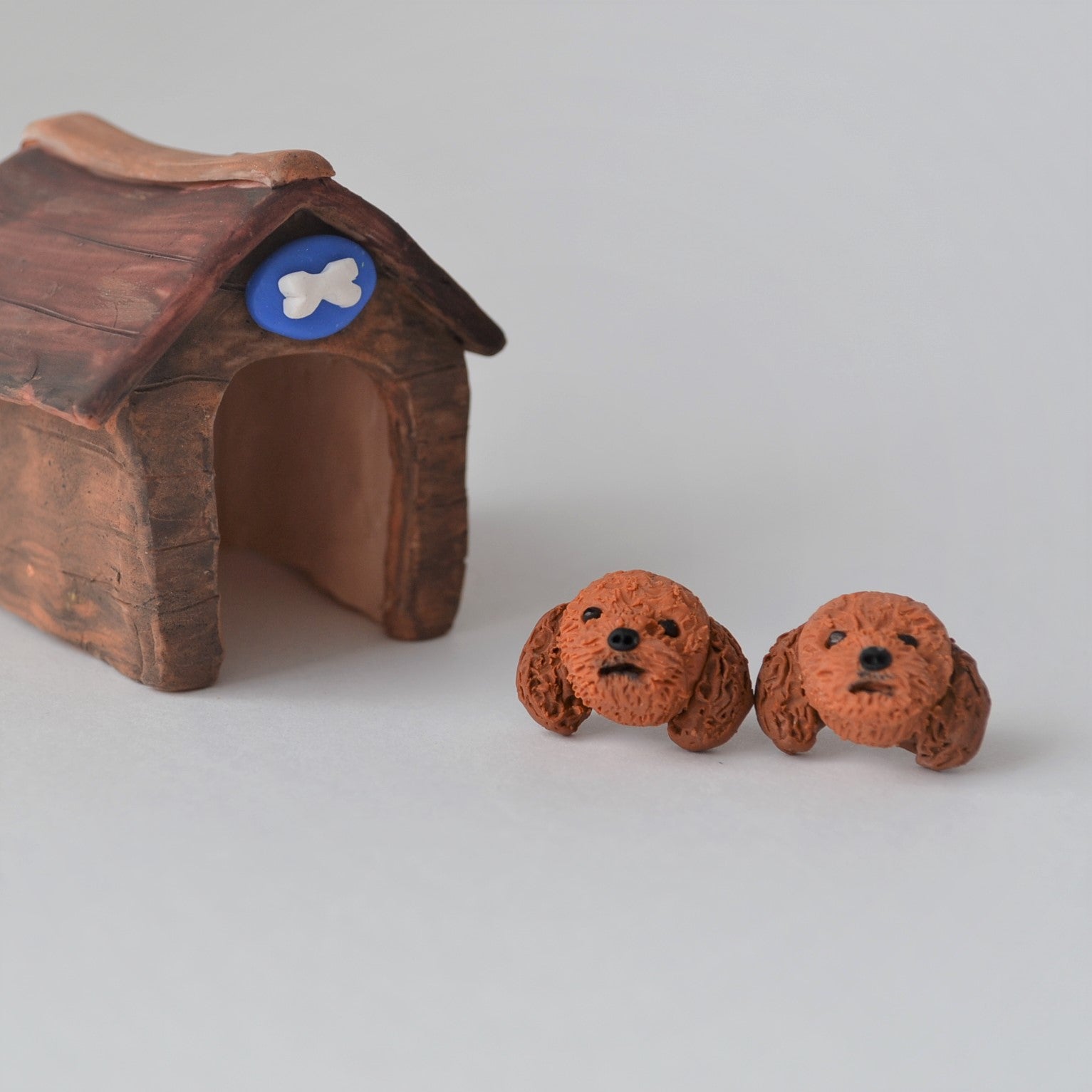 Handmade polymer clay Cavoodle stud earrings shown beside mini kennel