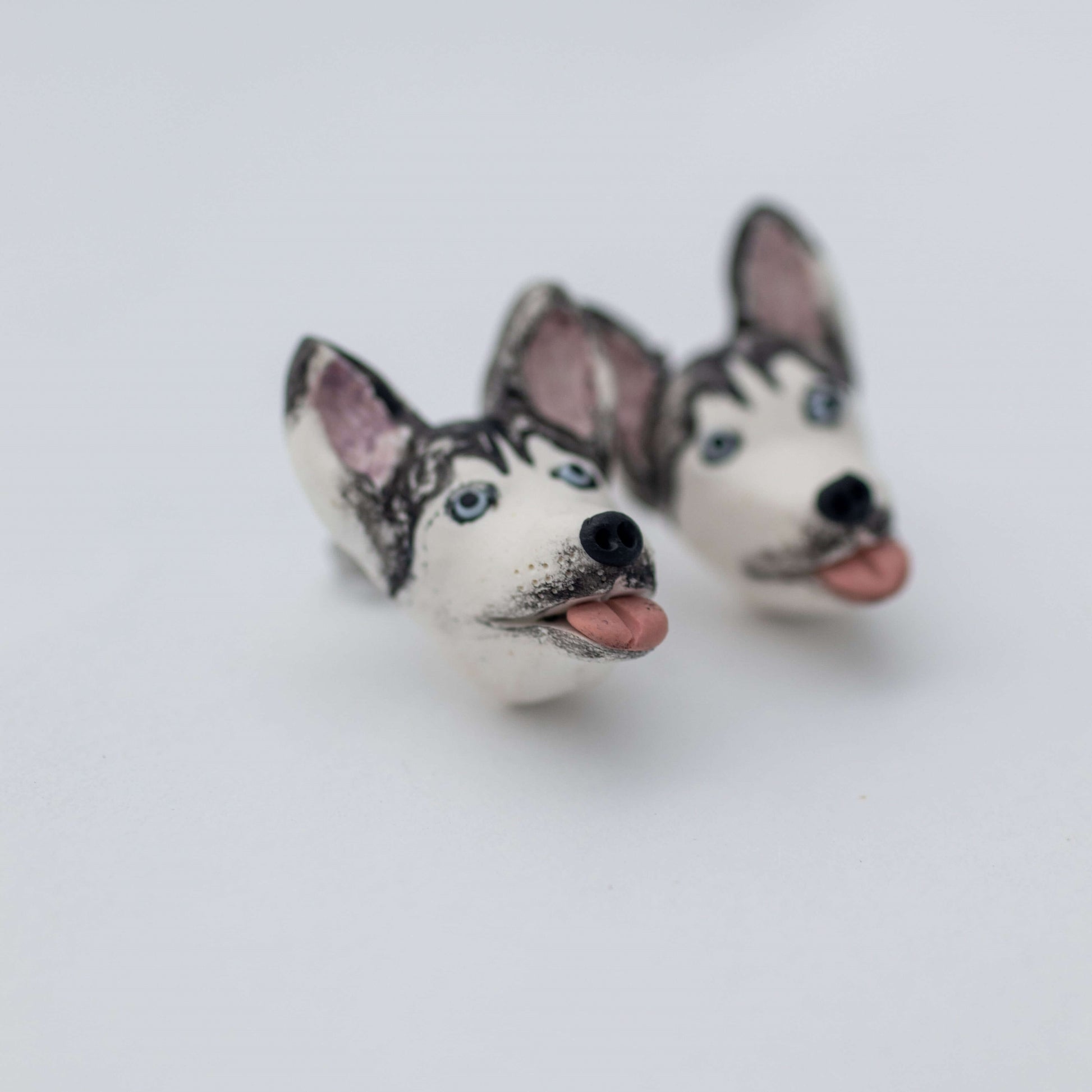 Handmade polymer clay husky stud earrings shown off cars up close