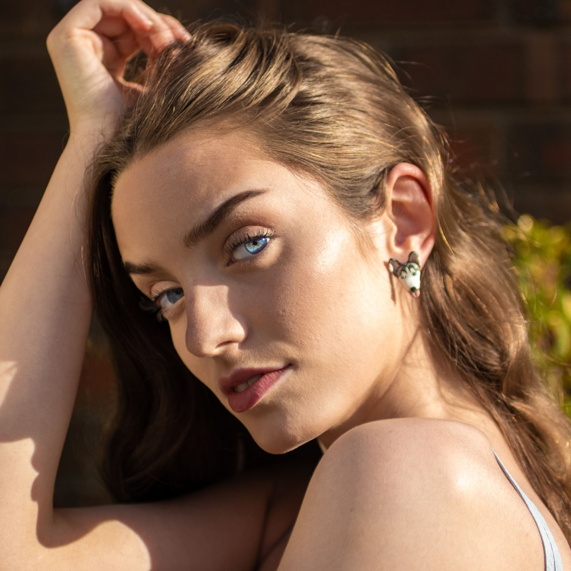 Handmade polymer clay husky stud earrings shown on model's ear