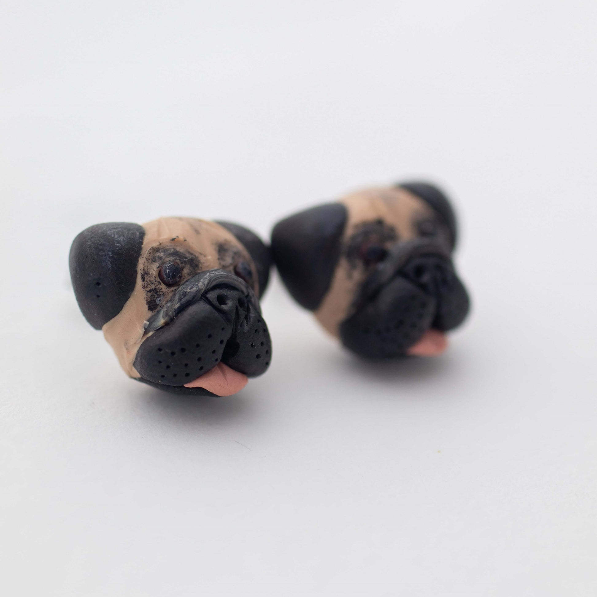 Handmade polymer clay pug stud earrings shown off card up close