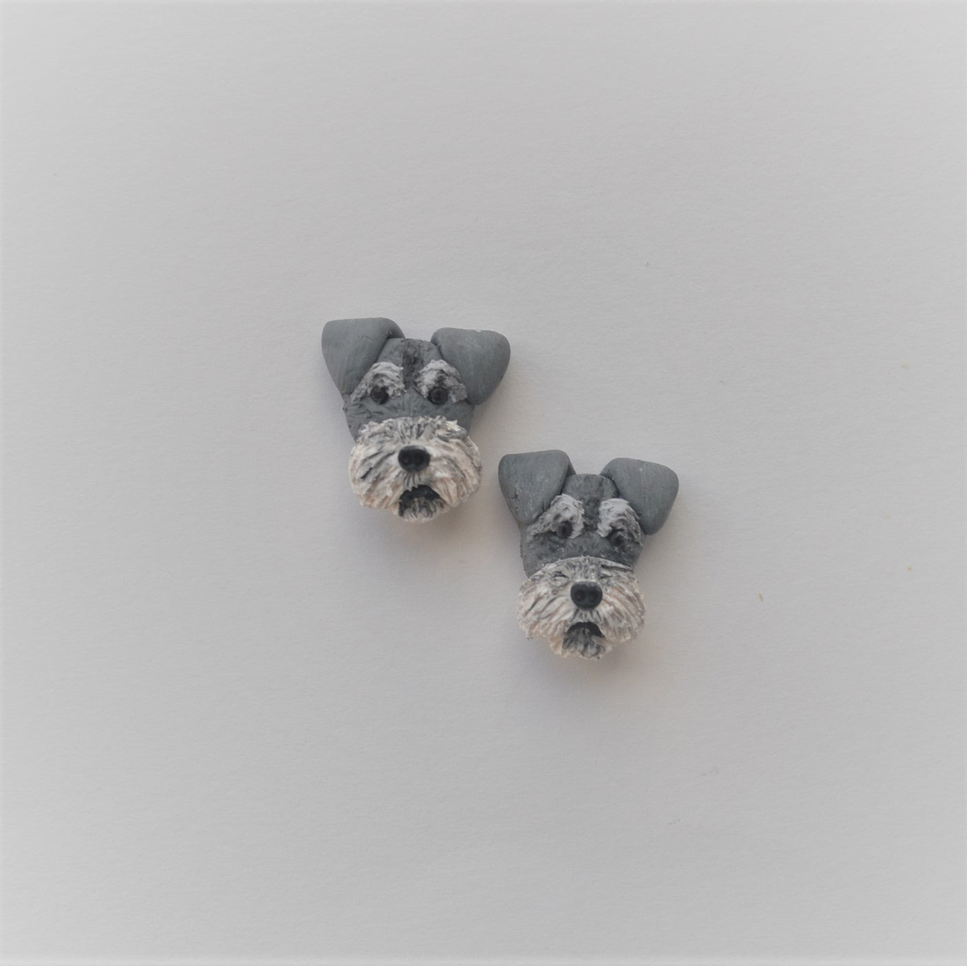 Handmade polymer clay schnauzer stud earrings shown offset on white background
