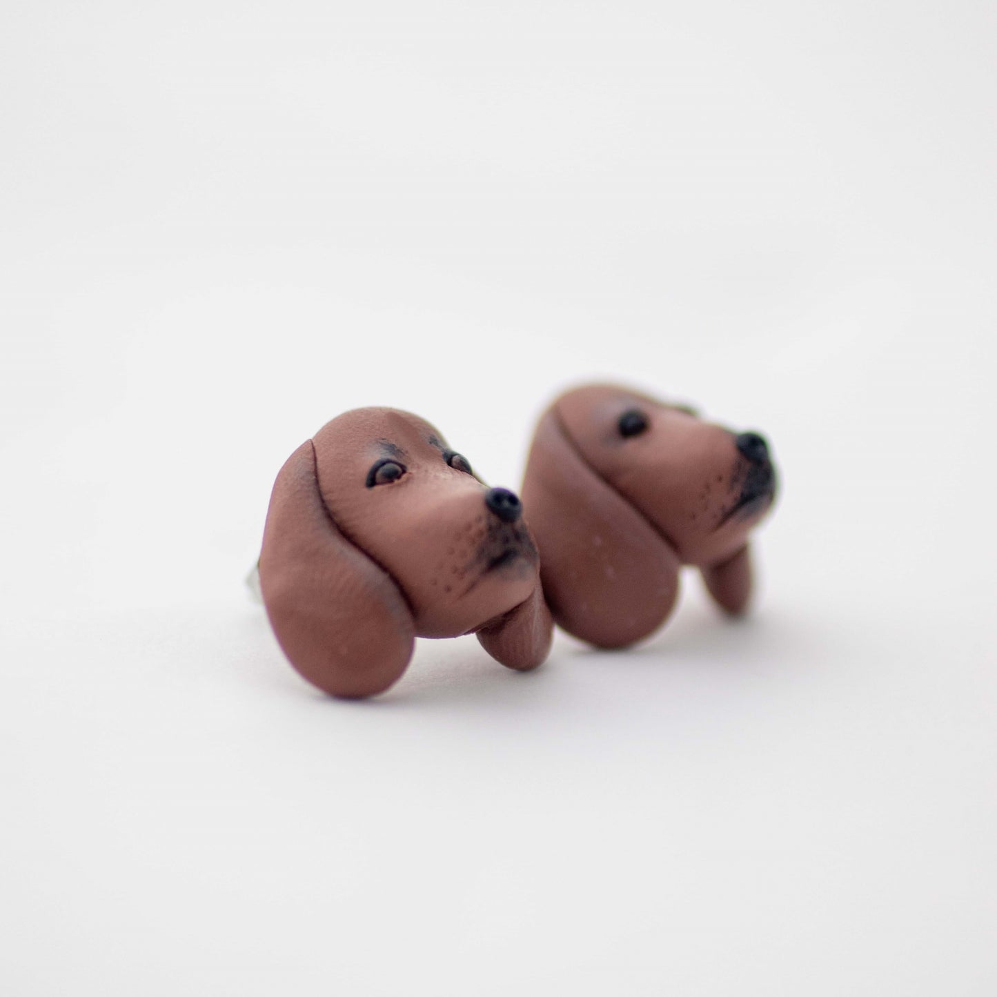 Handmade polymer clay Dachshund stud earrings shown on white background