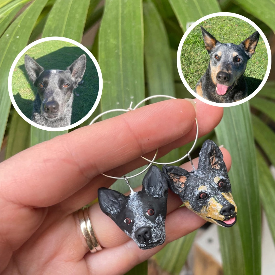 2 handmade wine glass charms of dogs being held.
