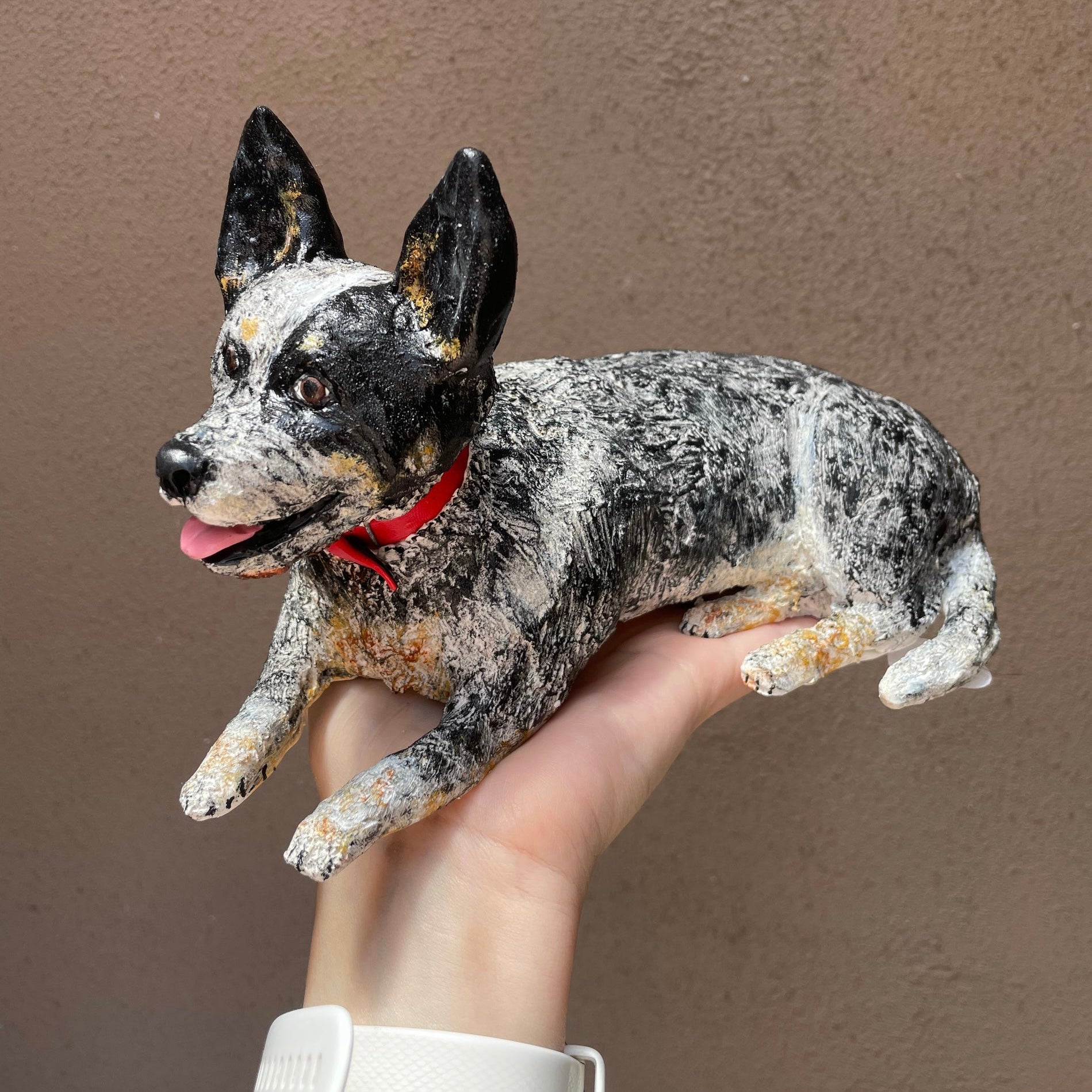 Large figuring of a blue heeler dog, sitting atop a hand.