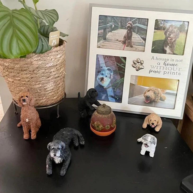 5 handmade custom dog figurines pictured in front of a photo frame containing photos of the same dogs.