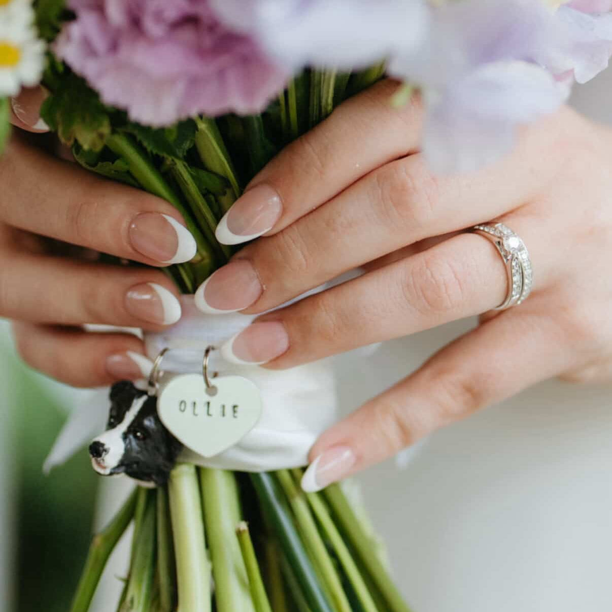 Close-up of hands holding a bouquet with custom border collie memorial bouquet charm.