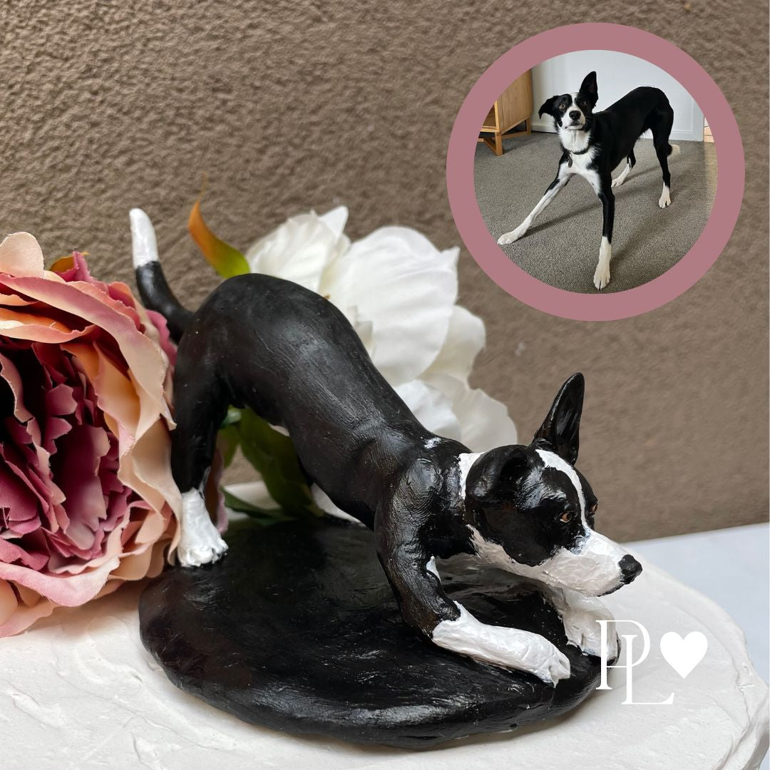 Handmade custom dog cake topper of a slender black and white dog on a base, shown as a wedding cake topper.