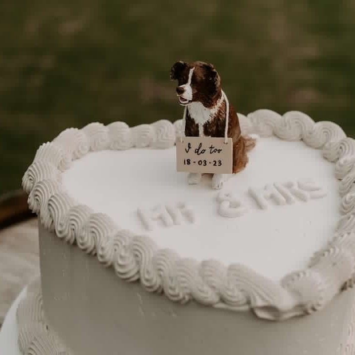Brown border collie custom dog wedding cake topper, positioned on a lambeth decorated heart-shape cake.
