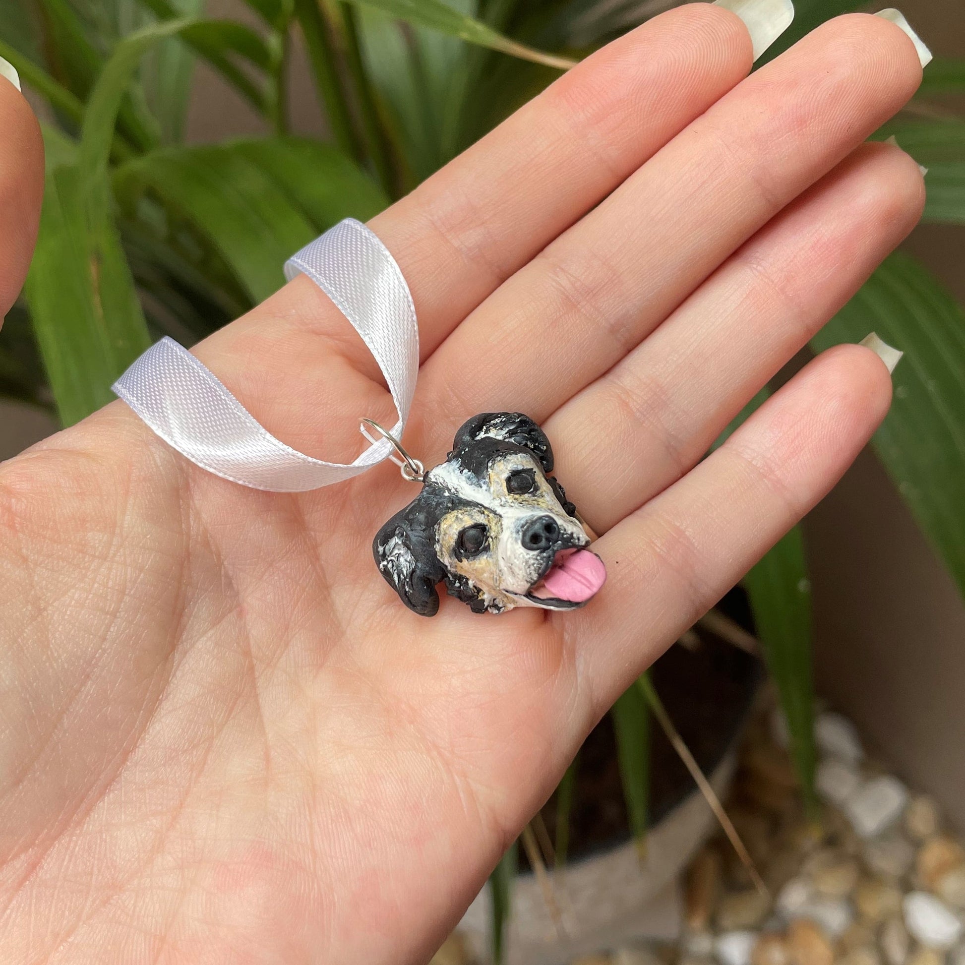 Handmade bouquet dog pendant on bouquet held over green palm plant background