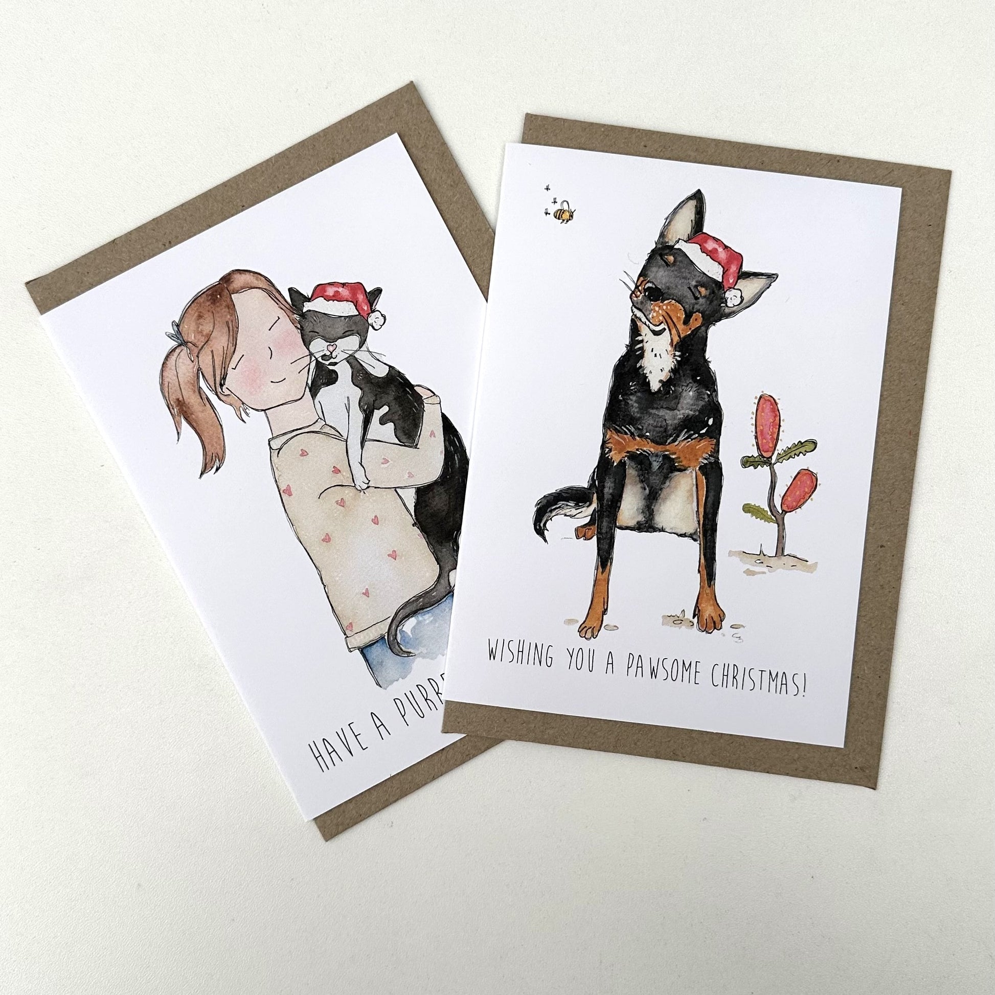 Two Christmas-themed greeting cards featuring illustrations of a girl with a cat and a dog with a Santa hat.
