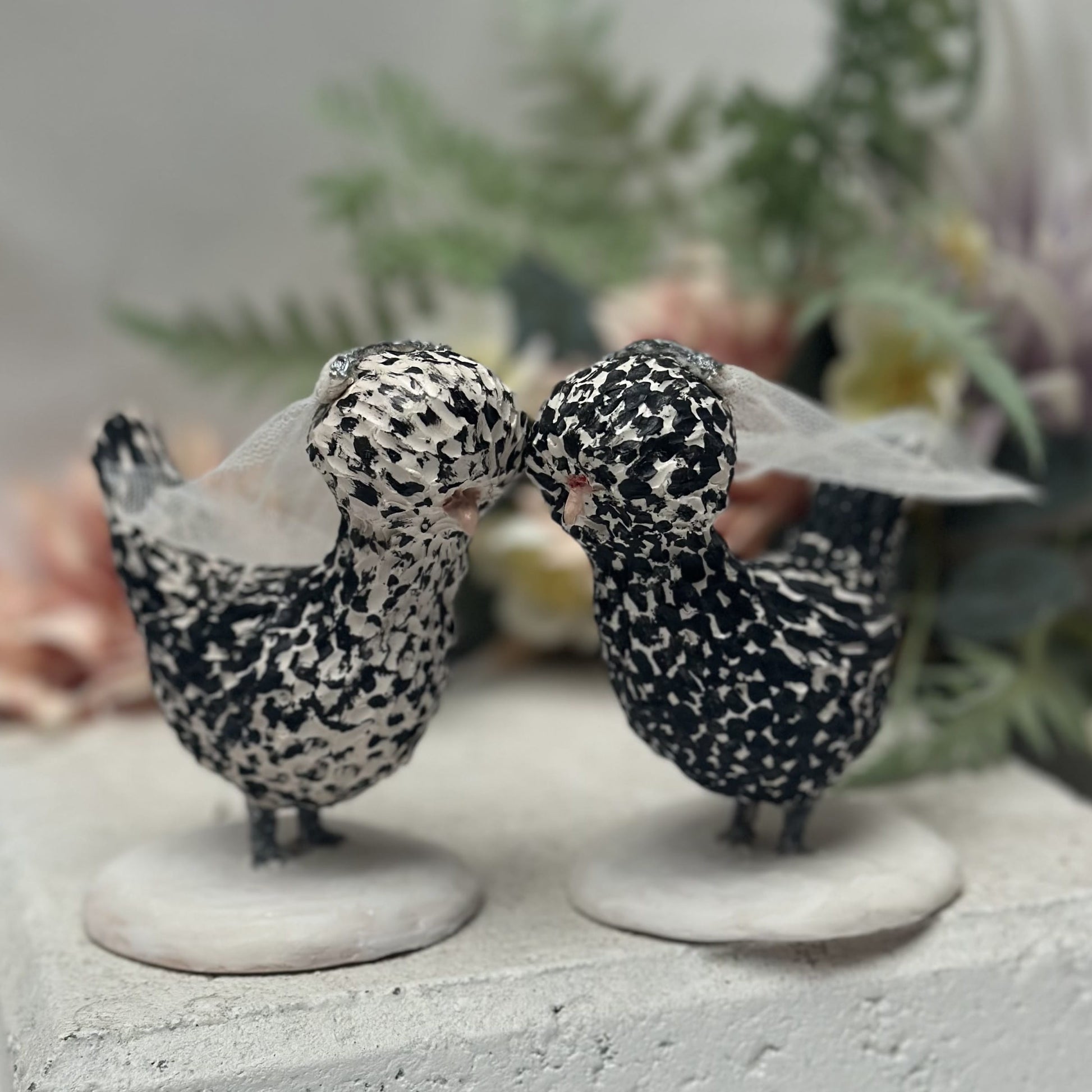 Two polymer clay handmade bird figurines with wedding attire on a neutral background