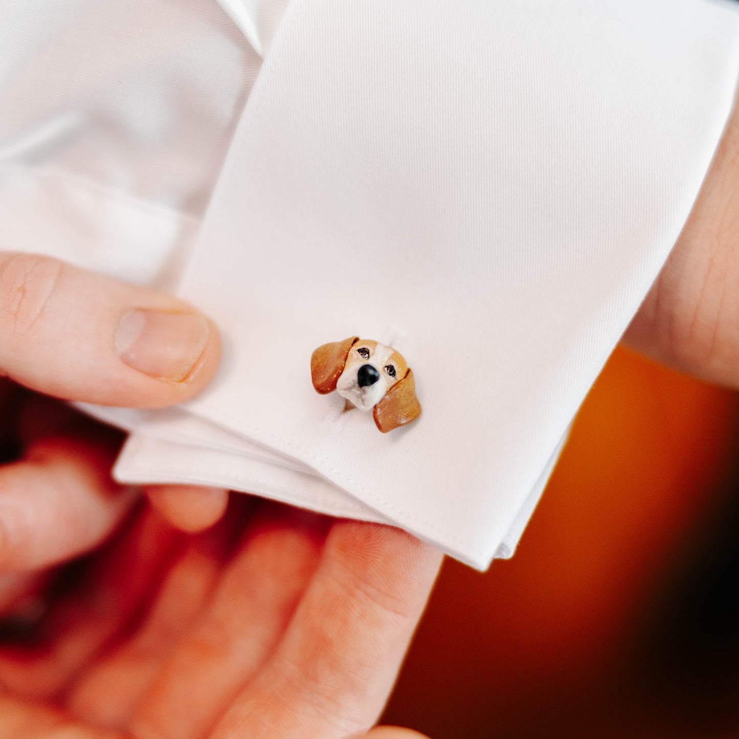 Cufflink with a dog design on a white shirt cuff.