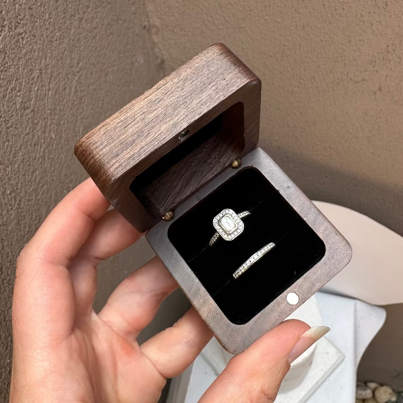 Double ring timber box being held with two diamond rings inserted in slots.
