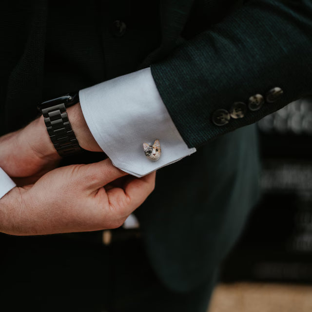 Cufflink with a cat design on a white cuff against a dark suit background