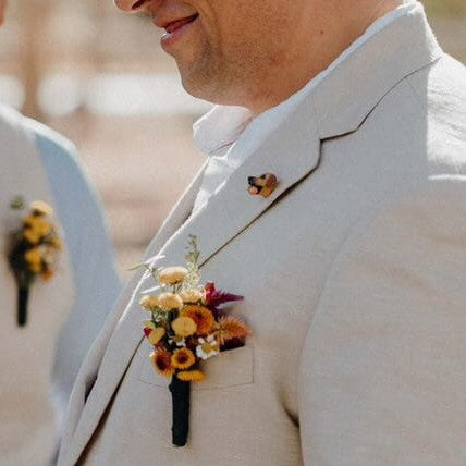 Man wearing a light-colored suit with a floral boutonniere and custom dog lapel pin.