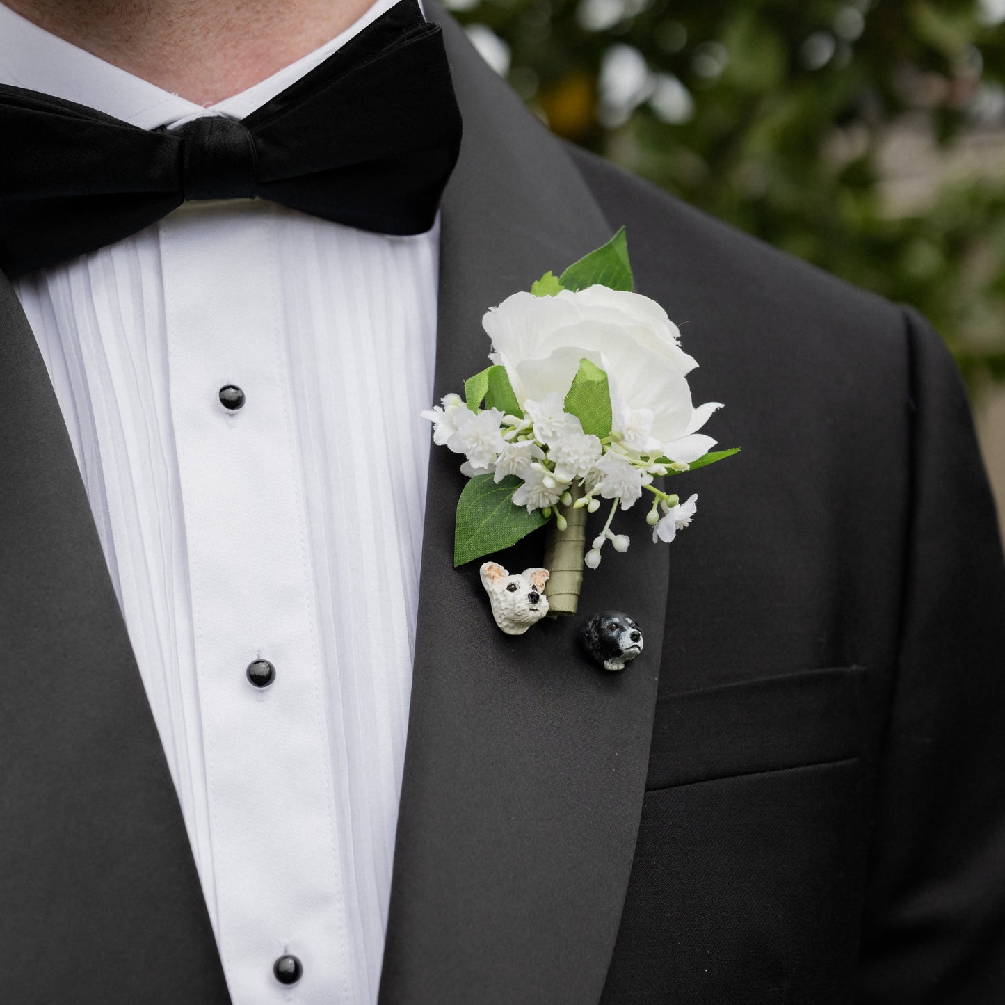 Tuxedo with a white floral boutonniere and small dog lapel pins on a blurred background