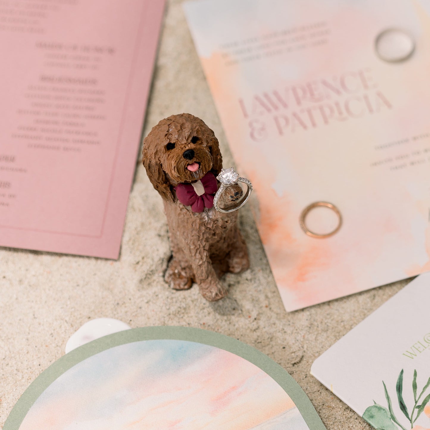 Small dog figurine with a ring on a textured surface with destination wedding stationery items.