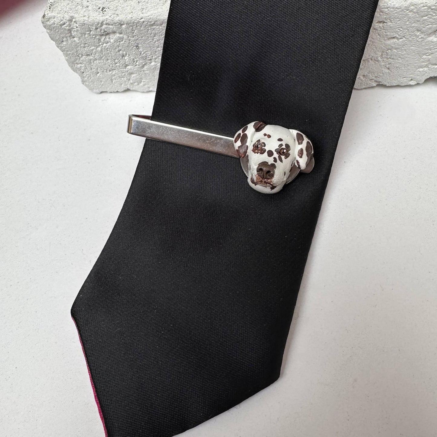 Black tie with a Dalmatian custom handmade tie clip on a light gray surface