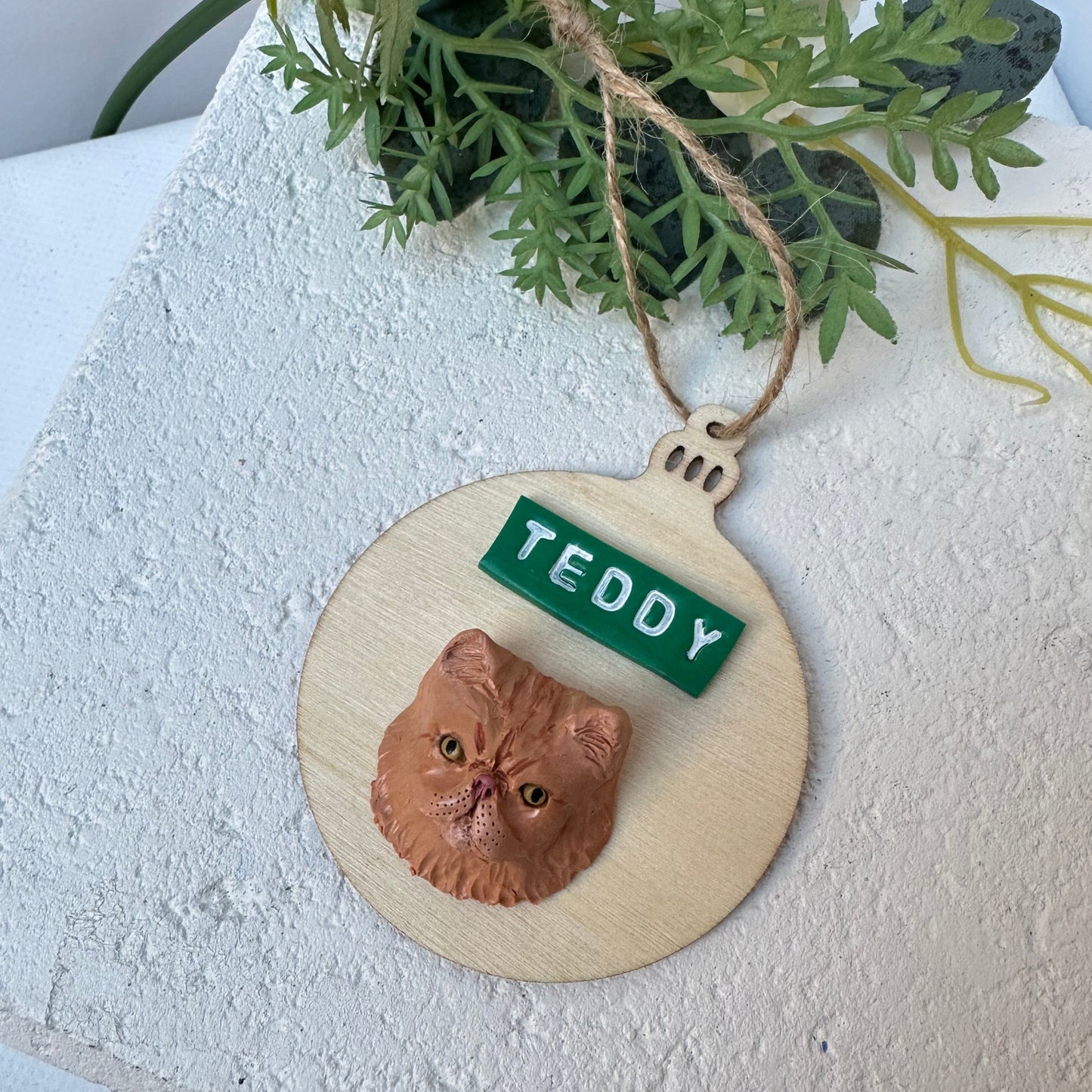 Bauble shaped timber Christmas ornament with polymer clay handmade cat face and name.